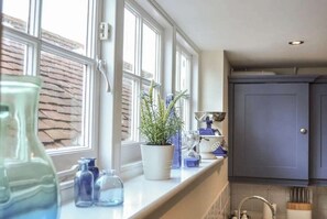 A kitchen with a window, a potted plant, and various kitchen items on the counter. - Starboard Light by NewFo dot Rest (Lymington)