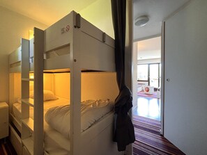 Ein Schlafraum mit Etagenbetten und einer Tür zu einem Badezimmer.