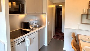 A compact kitchen with a built-in stove, a sink, and a small refrigerator. - Studio cabin, mountain view - 4 guests (Avoriaz)