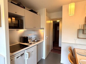 A compact kitchen with a built-in stove, a sink, and a small refrigerator. - Studio cabin, mountain view - 4 guests (Avoriaz)