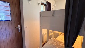 A bunk bed with a headboard, a door with a safety instructions poster, and a window with curtains. - Studio cabin, mountain view - 4 guests (Avoriaz)