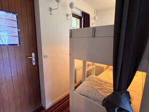 A bunk bed with a headboard, a door with a safety instructions poster, and a window with curtains. - Studio cabin, mountain view - 4 guests (Avoriaz)