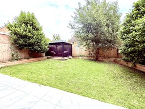 A backyard with a fenced area, a wooden deck, and a covered structure. - Vitre Gardens by NewFo dot Rest (Lymington)