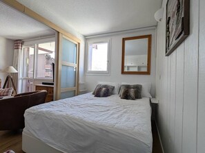 Ein Schlafzimmer mit Bett, Stuhl, Schreibtisch und Fenster.