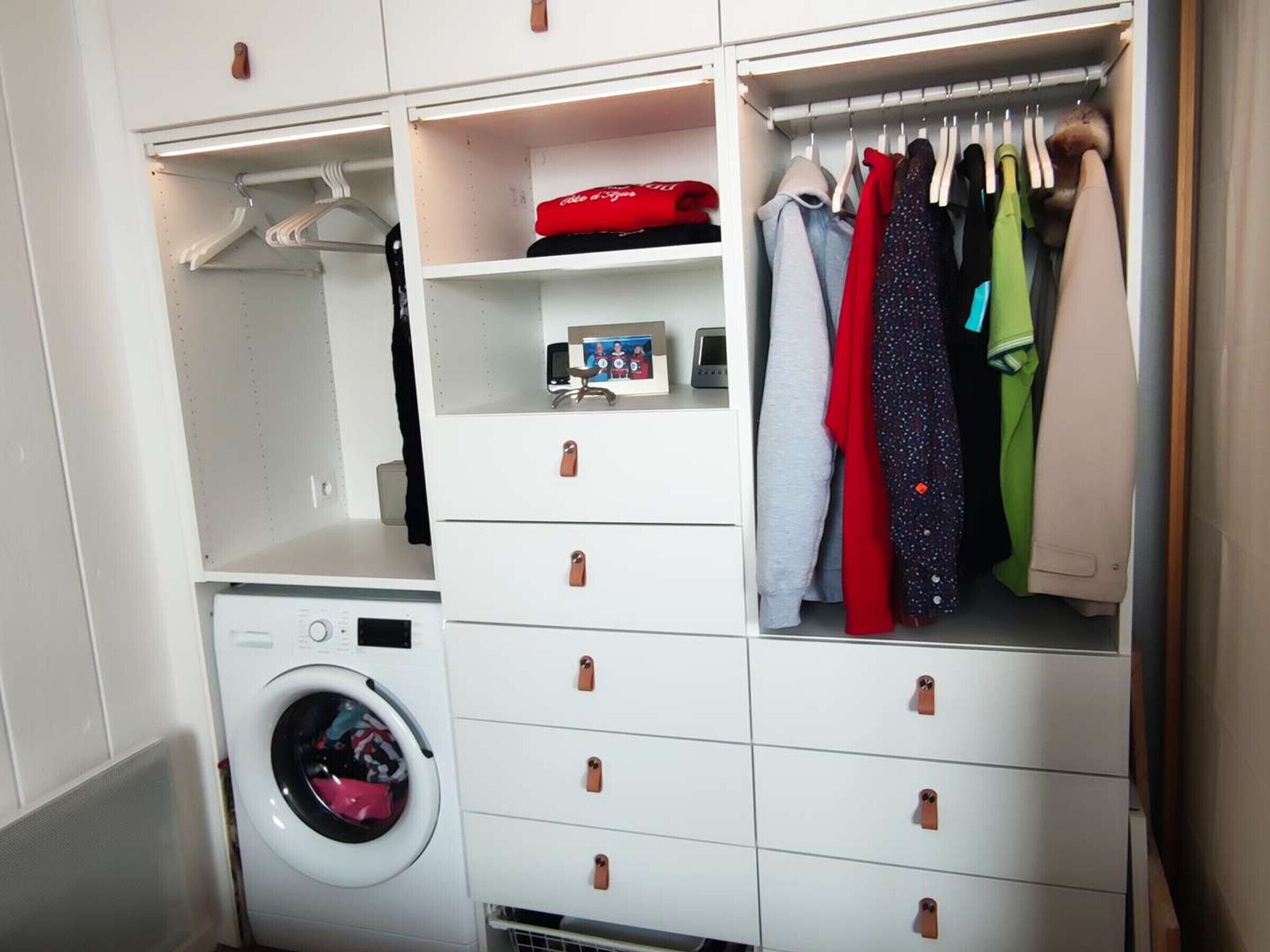 Ein kleiner Waschbereich mit Waschmaschine, Wäscheständer und Stauraum mit Schubladen und Platz zum Aufhängen.