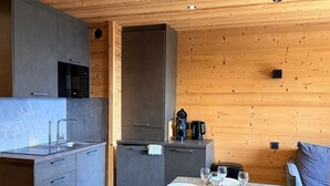 Moderni keittiö, jossa on harmaat kaapit, sisäänrakennettu mikroaaltouuni ja ruokailutila, jossa on neljälle katettu ruokapöytä.