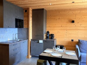 A modern kitchen with grey cabinets, a built-in microwave, and a dining area with a table set for four. - Contemporary chalet apartment - 8 guests (Chamrousse)