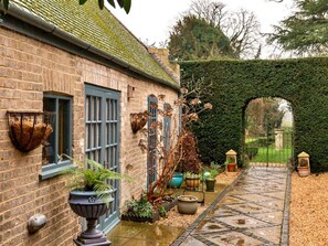 A brick building with a window, a door, and a wall-mounted basket. - Countryside Barn Near River Great Ouse (Huntingdon)