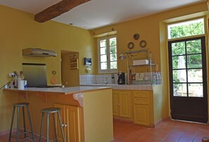 Une cuisine dotée d’un îlot central, de tabourets de bar, d’une cuisinière et d’une grande fenêtre.