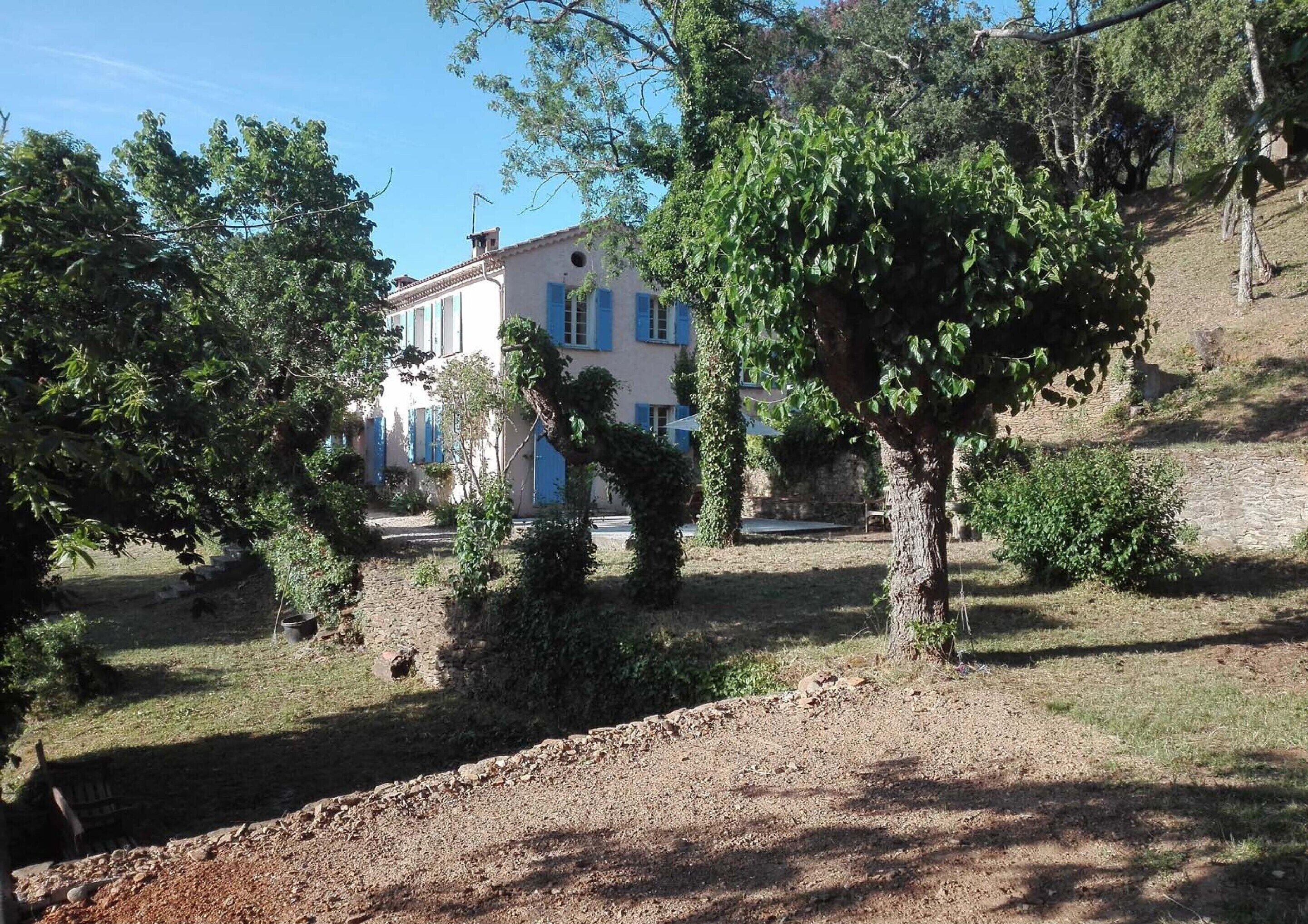 A building with a stone facade, surrounded by trees and a gravel path.
