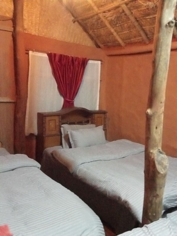 Una habitación con dos camas, un cabecero de madera y una ventana con cortina roja.