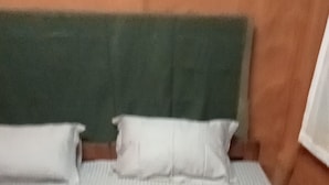 Een bed met een groen hoofdeinde en witte kussens.