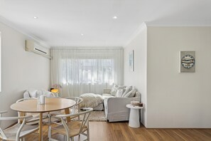 A modern living room with a round wooden table, white sofas, and a white floor. - Coastal living in beautiful Cottesloe (Cottesloe)
