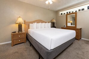 Ein ordentlich eingerichtetes Schlafzimmer mit einem Bett, zwei Nachttischen, einem Schranken und einem großen Spiegel.