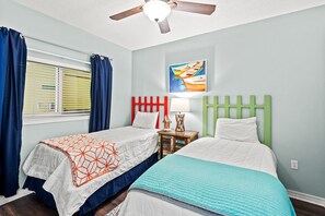 A bedroom with two beds, a ceiling fan, a window with blinds, and a painting on the wall. - 🏖️ Emerald Isle 1402 | 14th Floor Beachfront | 2 Pools + Walk to Pier (Gulf Breeze)