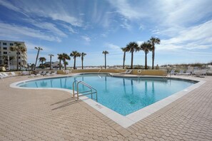 A swimming pool with lounge chairs and palm trees, surrounded by a paved area. - 🏖️ Emerald Isle 1402 | 14th Floor Beachfront | 2 Pools + Walk to Pier (Gulf Breeze)