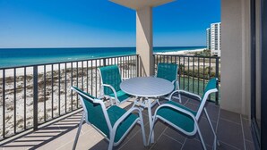 A balcony with a table and chairs, overlooking a beach and ocean. - Phoenix X 502 1 Bedroom Condo (Orange Beach)