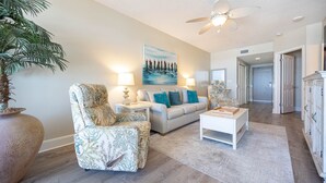 A living room with a sofa, armchair, coffee table, and a painting on the wall. - Phoenix X 502 1 Bedroom Condo (Orange Beach)