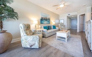 Un salon comprenant un canapé, un fauteuil, une table basse et un tableau accroché au mur.