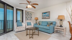 A living room with a sofa, two armchairs, a coffee table, and a ceiling fan. - Phoenix Iii 3096 2 Bedroom Condo (Orange Beach)
