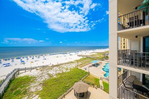 A beach view from a balcony with a pool and beach umbrellas. - Phoenix Iii 3053 1 Bedroom Condo (Orange Beach)