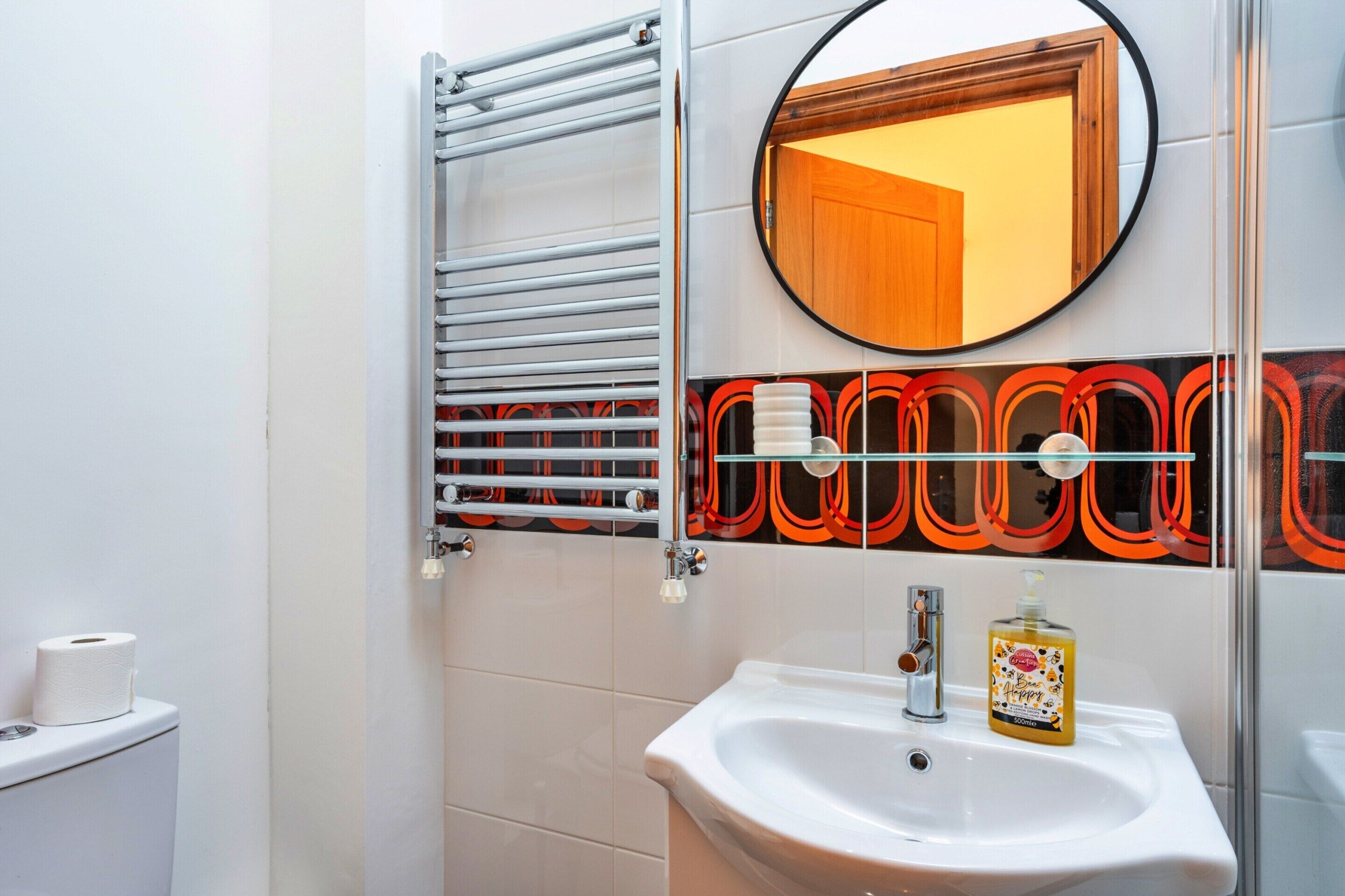 A bathroom with a white sink, a mirror, a towel rack, and a toilet.