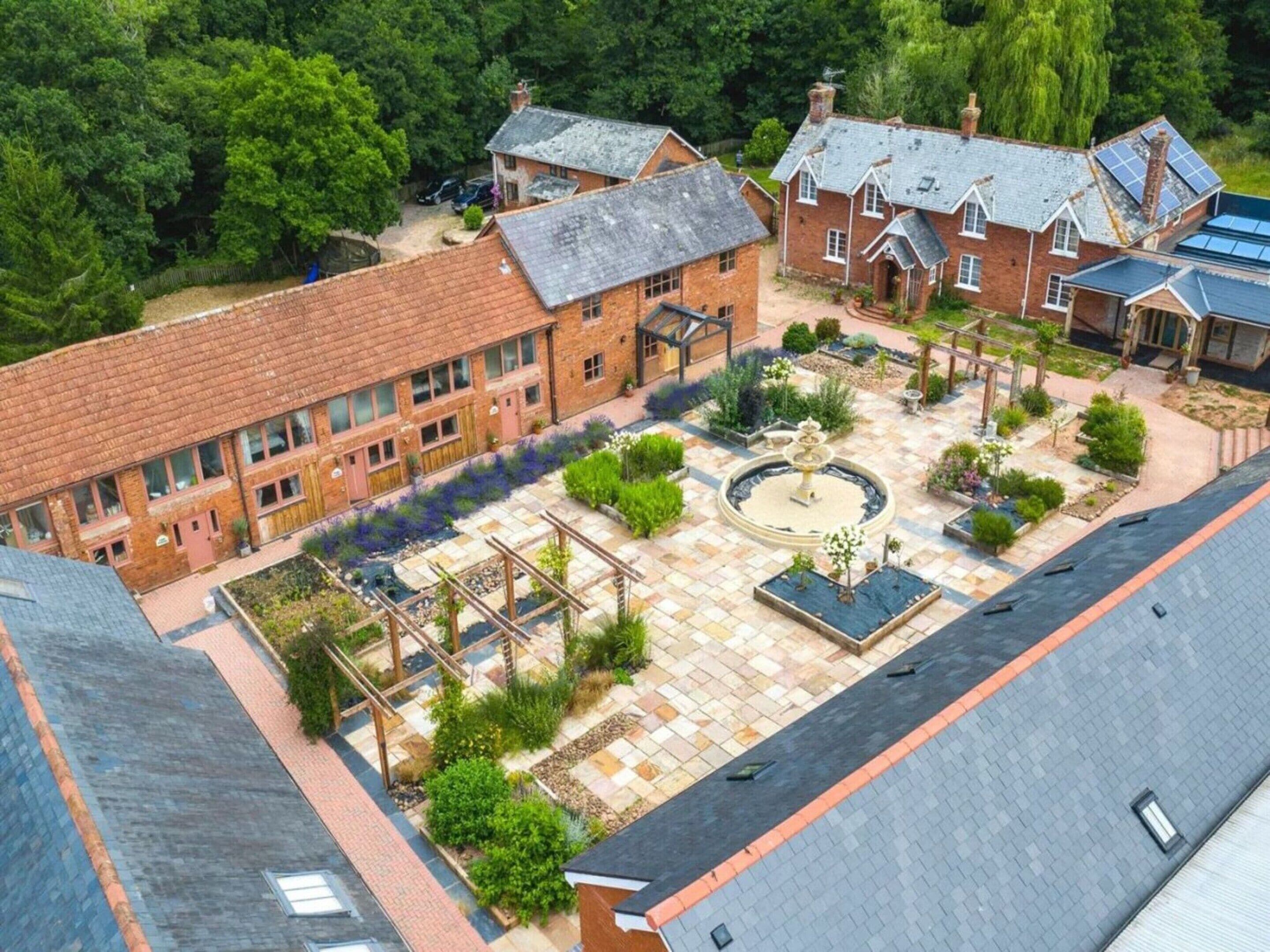 A courtyard with a central fountain, surrounded by brick buildings with multiple windows and a garden area.