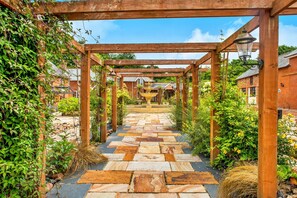 A wooden pergola structure with a stone pathway leading to a garden area. - Devon Cottage With Games Room (Exeter)