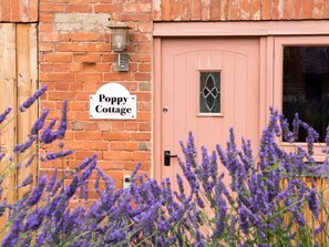 A brick wall with a sign reading 'Poppy Cottage' and a pink door with a window. - Devon Cottage With Games Room (Exeter)