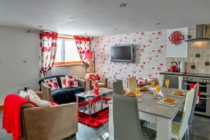 A modern living room with a sofa, a coffee table, and a TV mounted on the wall. - Devon Cottage With Games Room (Exeter)