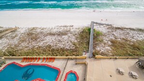 A beach view with a pool area, including a pool, lounge chairs, and a lifeguard stand. - Phoenix Iii 3095 1 Bedroom Condo (Orange Beach)