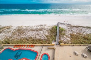 A beach view with a pool area, including a pool, lounge chairs, and a lifeguard stand. - Phoenix Iii 3095 1 Bedroom Condo (Orange Beach)