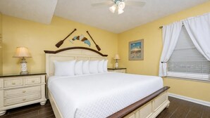 A bedroom with a large bed, two bedside tables, a ceiling fan, and a window with curtains. - Phoenix Iii 3095 1 Bedroom Condo (Orange Beach)