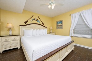 A bedroom with a large bed, two bedside tables, a ceiling fan, and a window with curtains. - Phoenix Iii 3095 1 Bedroom Condo (Orange Beach)