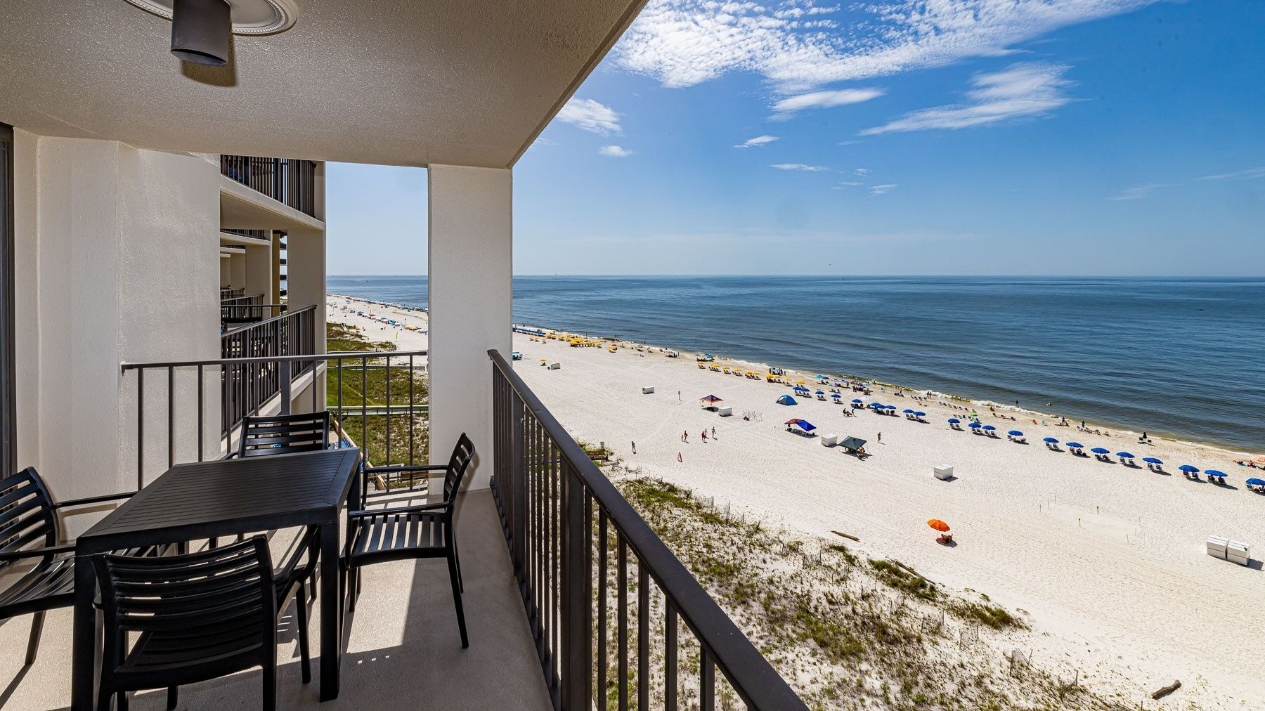 Ein Balkon mit Blick auf einen Strand, einem Tisch und Stühlen.