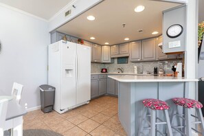 Una cocina moderna con una isla integrada, armarios grises, un dispensador de agua y un reloj en la pared.
