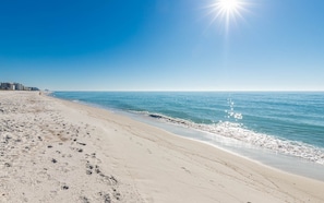 Uma praia com céu limpo e o sol brilhando.