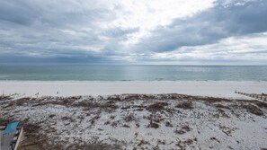 Een strand met zand aan de voorgrond en een houten omheining langs de waterlijn.