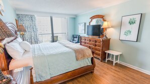 A hotel room with a large bed, a dresser, a television, and a small table. - 705 S Hampton Oceanview Retreat With Balcony 2 Bedroom Condo (Myrtle Beach)
