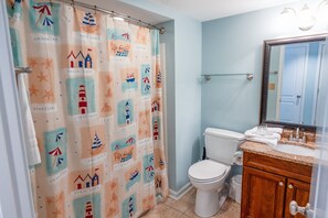 A bathroom with a shower curtain featuring nautical designs, a toilet, a vanity with a mirror, and a sink. - 705 S Hampton Oceanview Retreat With Balcony 2 Bedroom Condo (Myrtle Beach)