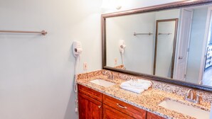 A bathroom with a double sink vanity, a large mirror, and two hair dryers mounted on the wall. - 705 S Hampton Oceanview Retreat With Balcony 2 Bedroom Condo (Myrtle Beach)