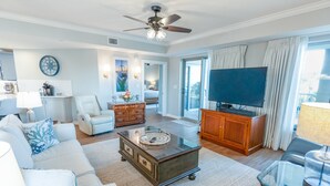 A spacious living room with a ceiling fan, a flat-screen TV, a coffee table, and a sofa. - 102 Royale Palms Oceanfront 2br Resort Access 2 Bedroom Condo (Myrtle Beach)