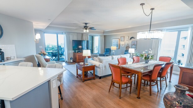 A modern living room with a dining area, a flat-screen TV, and a chandelier. - 102 Royale Palms Oceanfront 2br Resort Access 2 Bedroom Condo (Myrtle Beach)