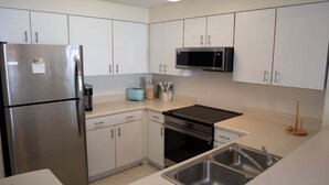 A modern kitchen with stainless steel appliances, white cabinets, and a built-in microwave. - Pelican Beach 1013 2 Bedroom Condo (Destin)