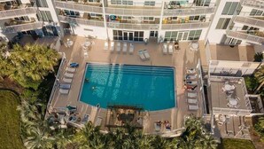 An aerial view of a hotel with a central swimming pool surrounded by sun loungers and a palm tree-lined deck. - Terrace At Pelican Beach 0804 3 Bedroom Condo (Destin)