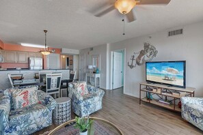 A living room with a sofa set, a television, and a dining area with chairs and a table. - Terrace At Pelican Beach 0804 3 Bedroom Condo (Destin)