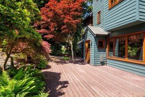 Una terraza de madera que conduce a una casa con fachada azul y un pequeño porche.