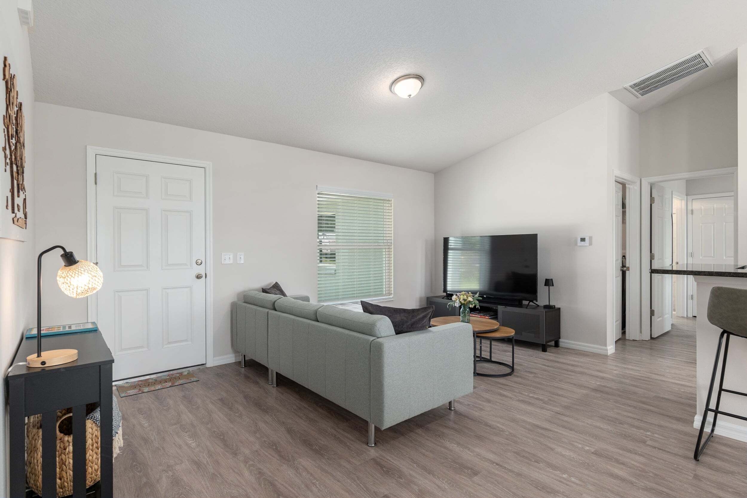 A modern living room with a grey sofa, a television, and a wooden floor.