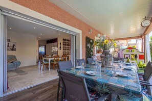 A dining area with a table set for four, a bookshelf, and a children's play area visible through an open door. - Charming ground floor villa apartment with a heated swimming pool (Cers)