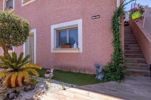 A pink building with a window, a small garden with a palm tree, and a statue. - Charming ground floor villa apartment with a heated swimming pool (Cers)